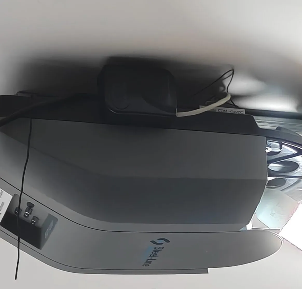 Looking up at the Steel-line SD1200 on the garage ceiling, with the black GE-RCV1 box mounted on top of the motor and its wires running to the motor’s terminals
