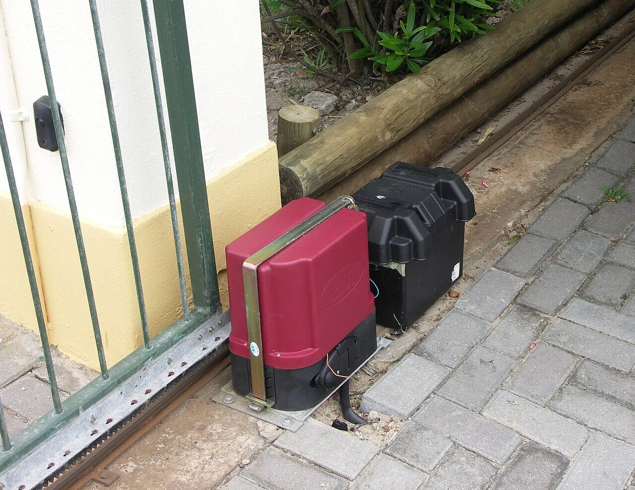 A sliding gate with its electric motor, backup battery box and toothed track
